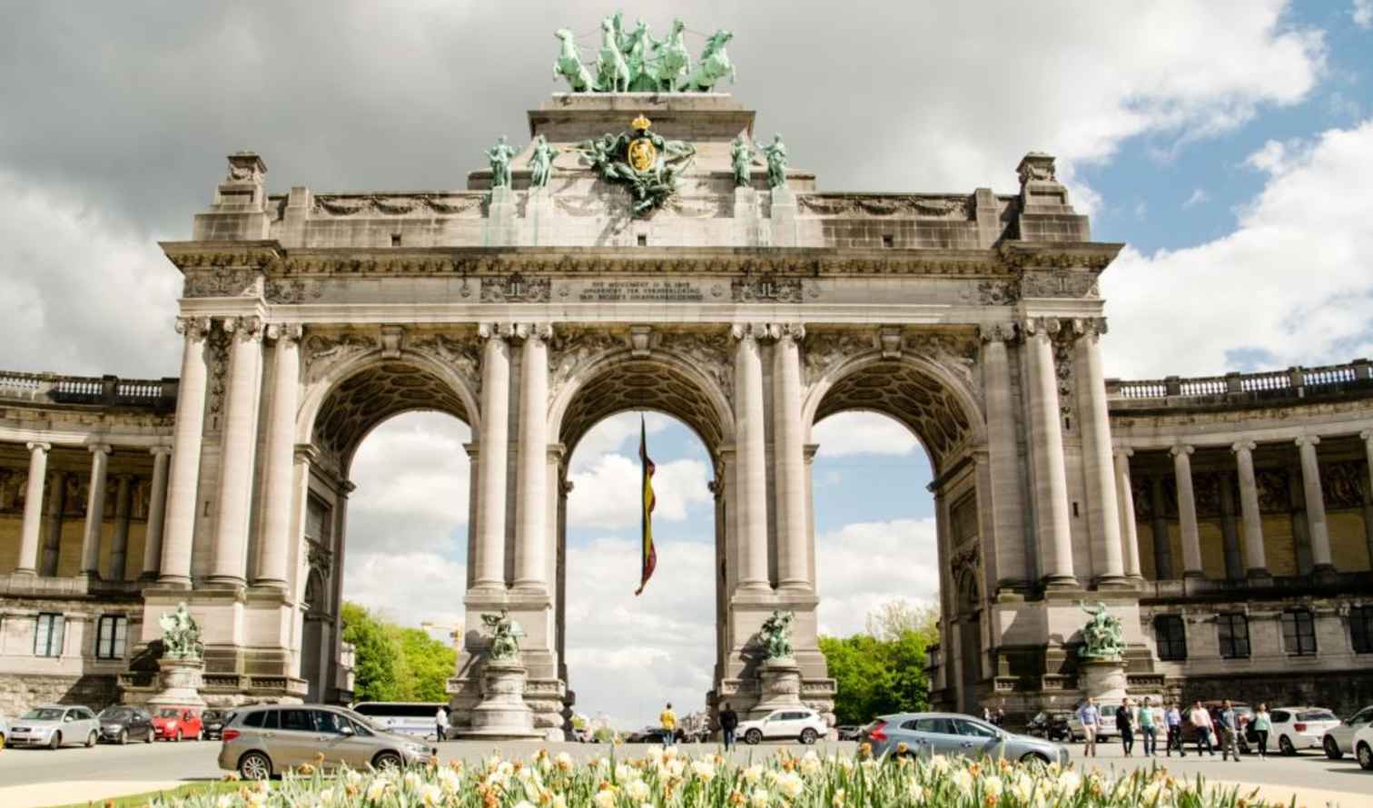 The Triumphal Arch at Cinquantenaire Park in Brussels under a cloudy sky.