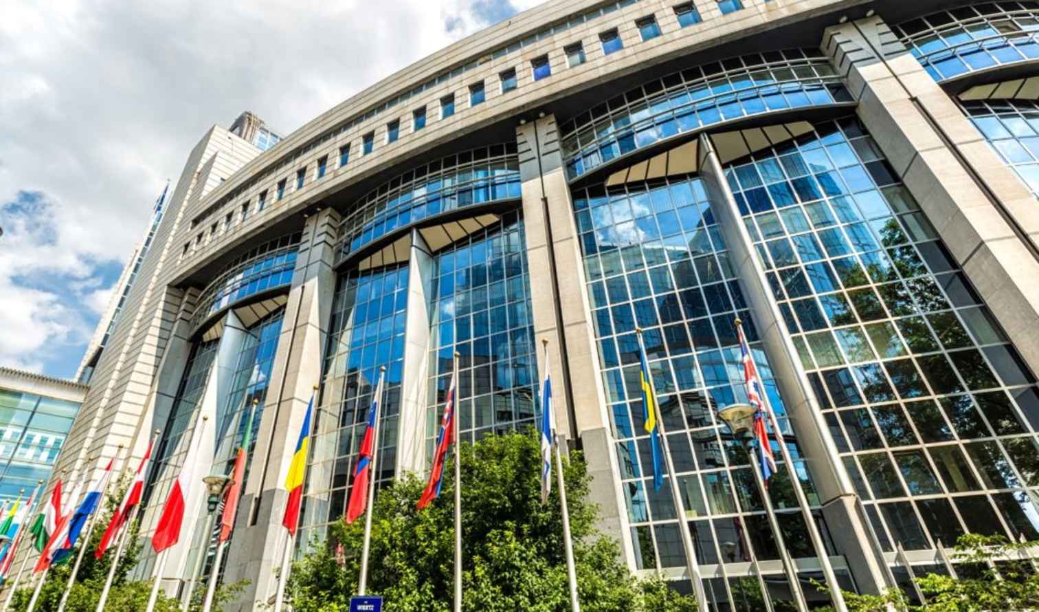 European Parliament building with numerous flags in Brussels, Belgium.