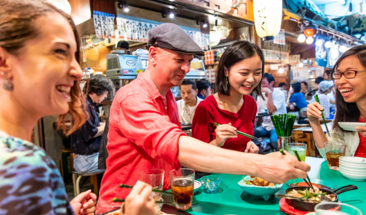 People dining in a Japanese izakaya with food and drinks on the table in Tokyo.