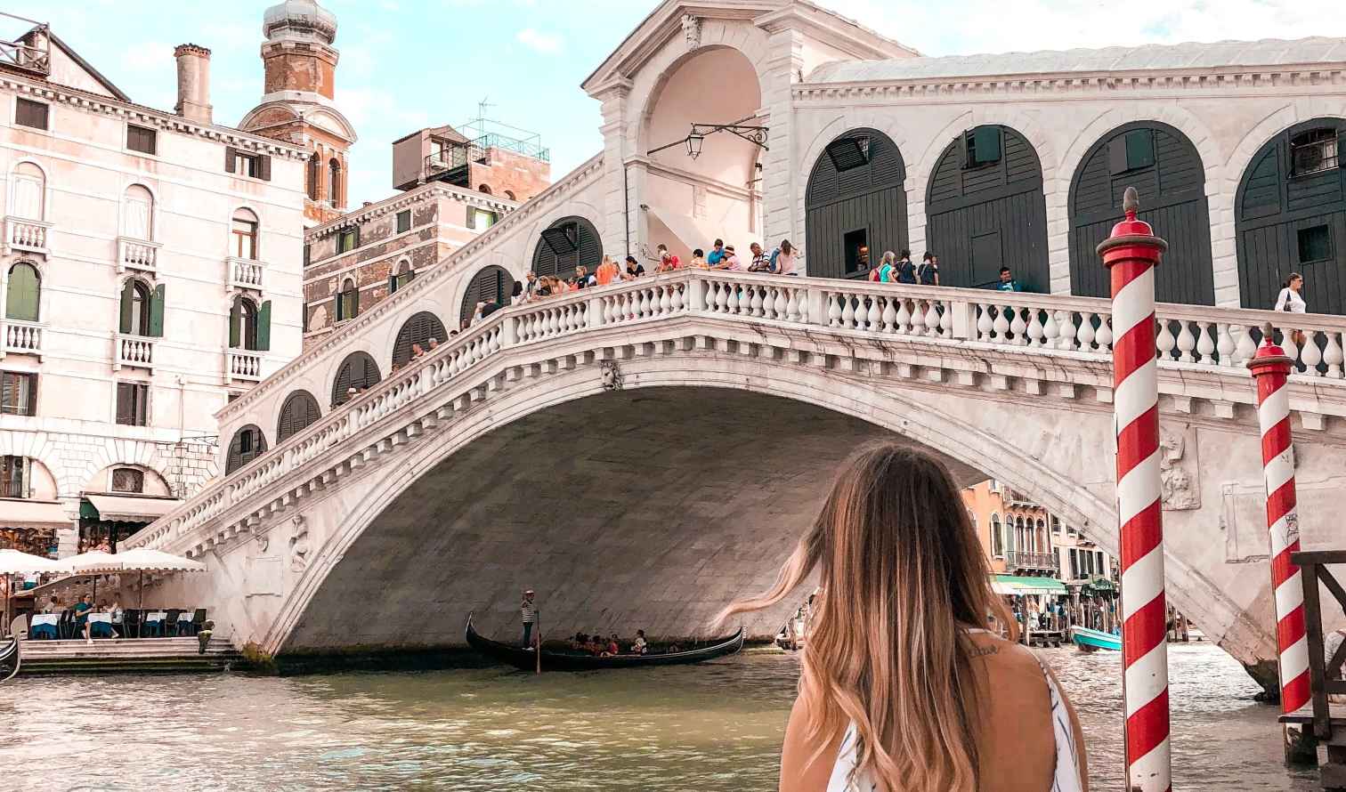 Woman sitting near the Rialto Bridge in Venice, Italy.