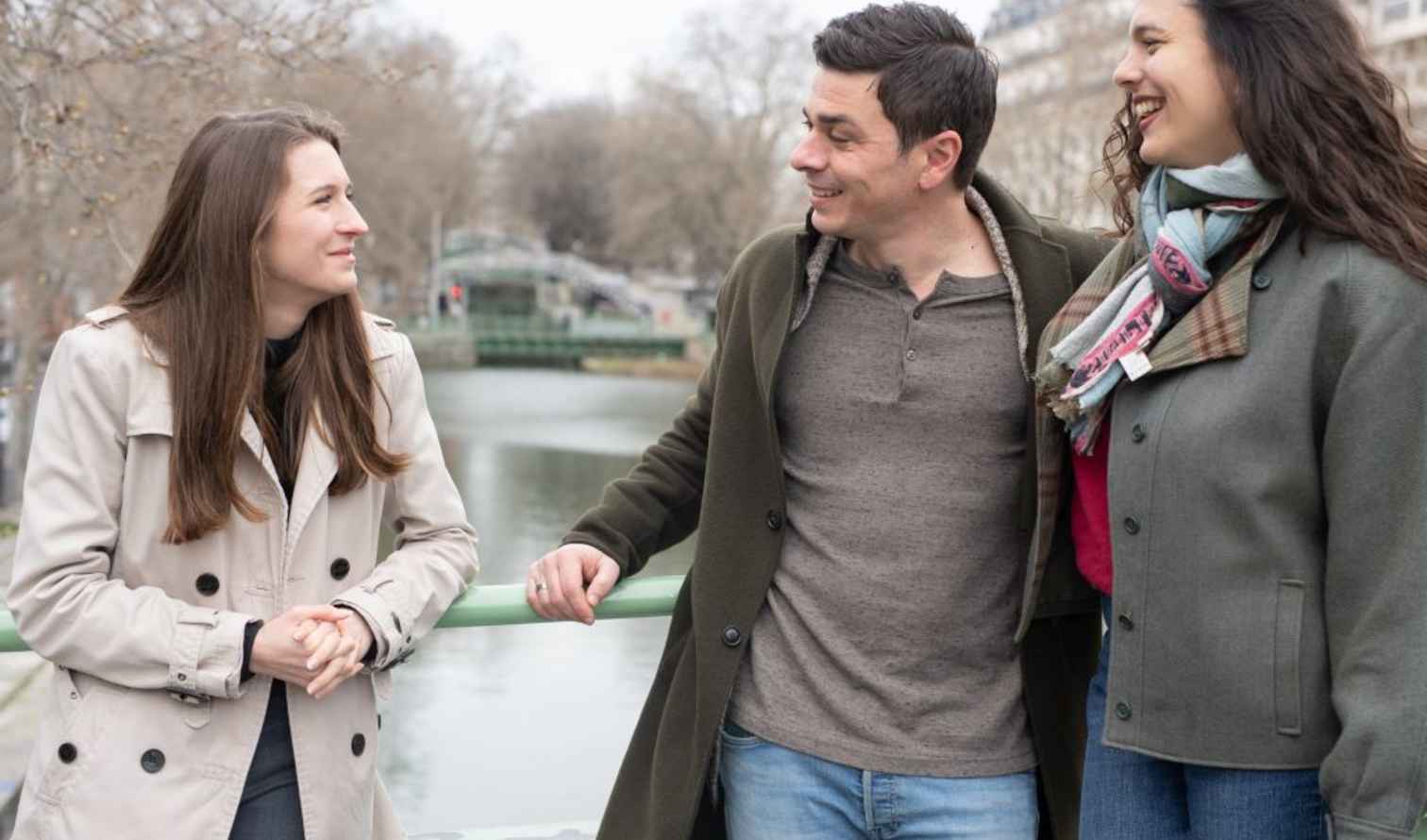 Three people standing on a bridge over Canal Saint-Martin in Paris.