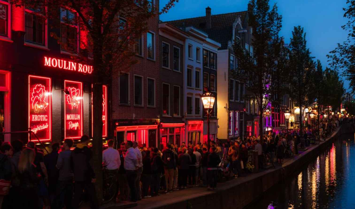 Crowds outside Moulin Rouge nightclub in Amsterdam's Red Light District at night.