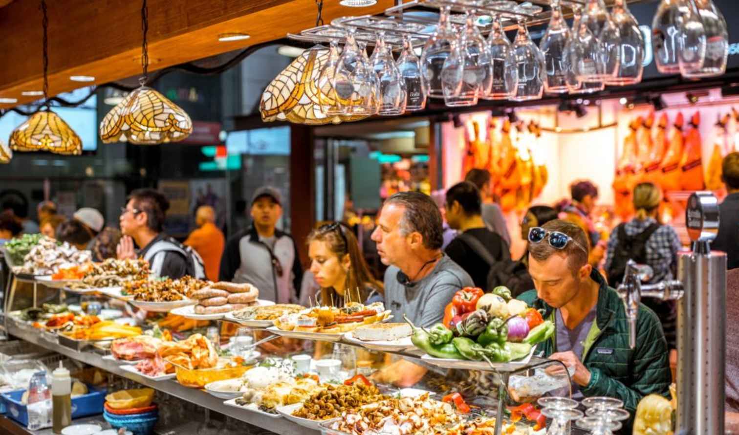 People dining at a tapas bar in La Boqueria Market, Barcelona.