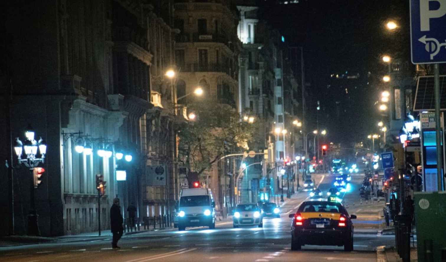 Night street scene in Barcelona, Spain, with cars and lit buildings.
