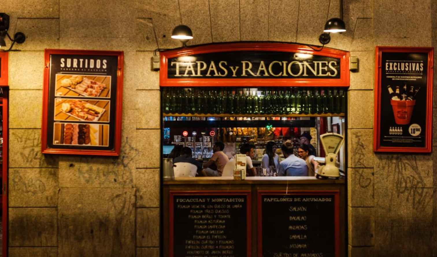 Tapas restaurant facade with people dining inside in Madrid.