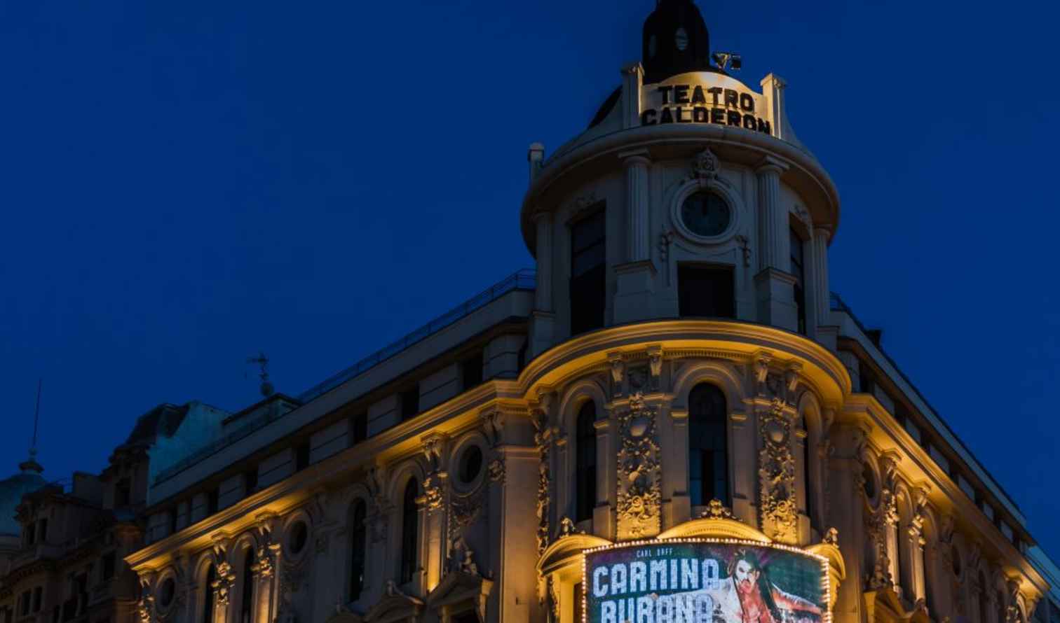 Teatro Calderón lit up at night with a Carmina Burana poster visible in Madrid