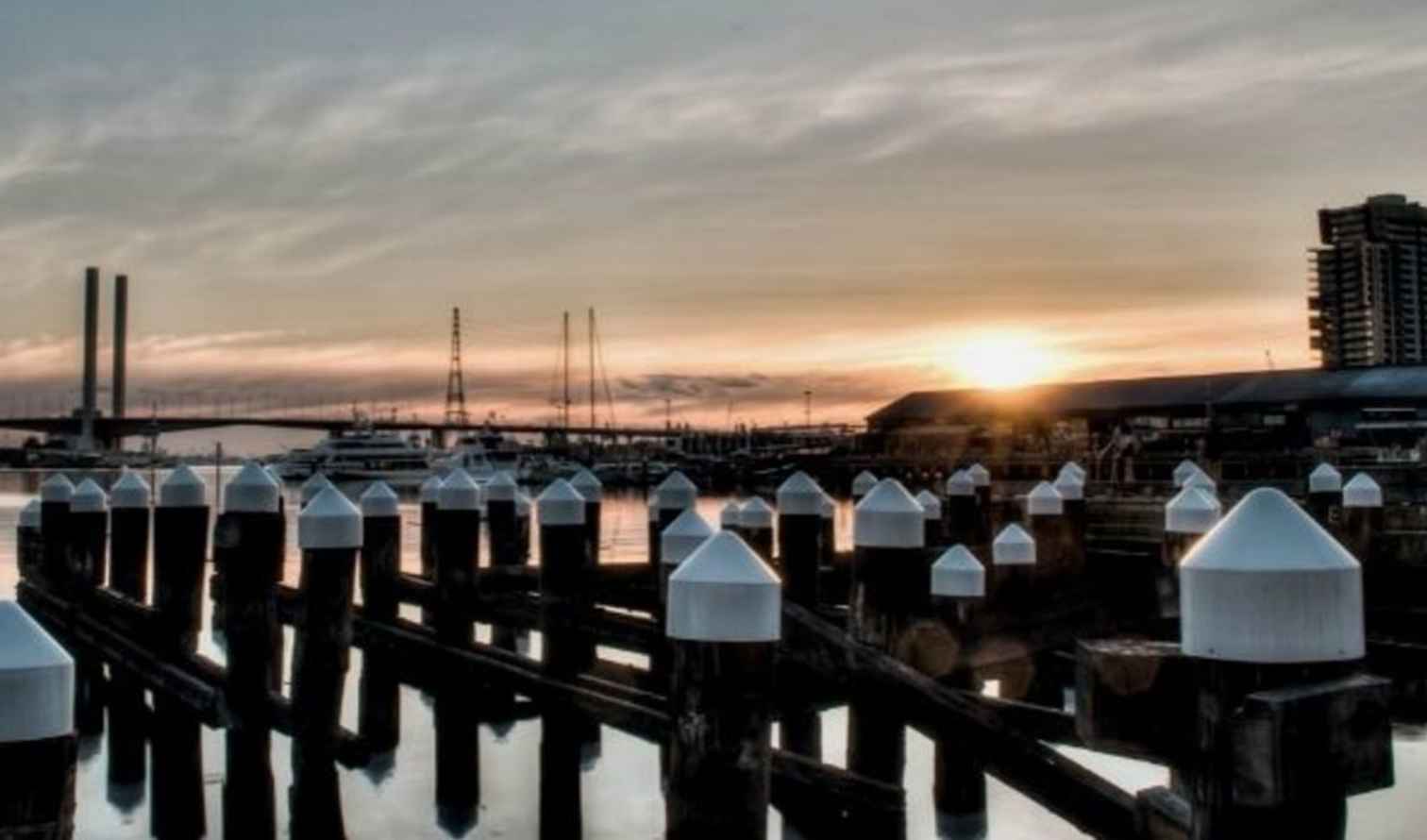 Docklands harbor at sunset with Melbourne Star Observation Wheel in the background.