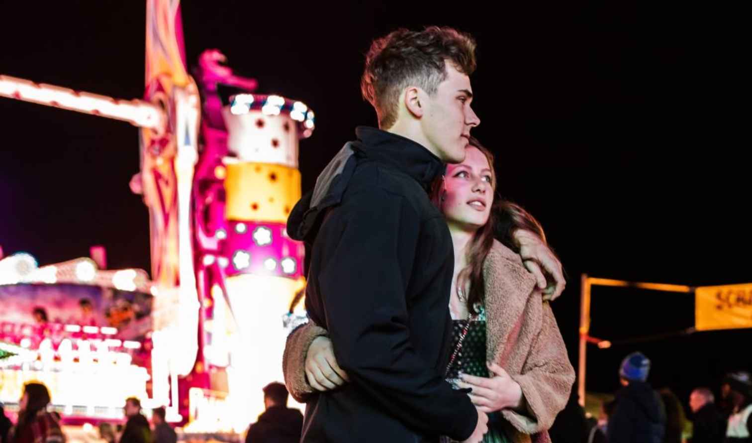 A couple stands together at a nighttime carnival in Munich