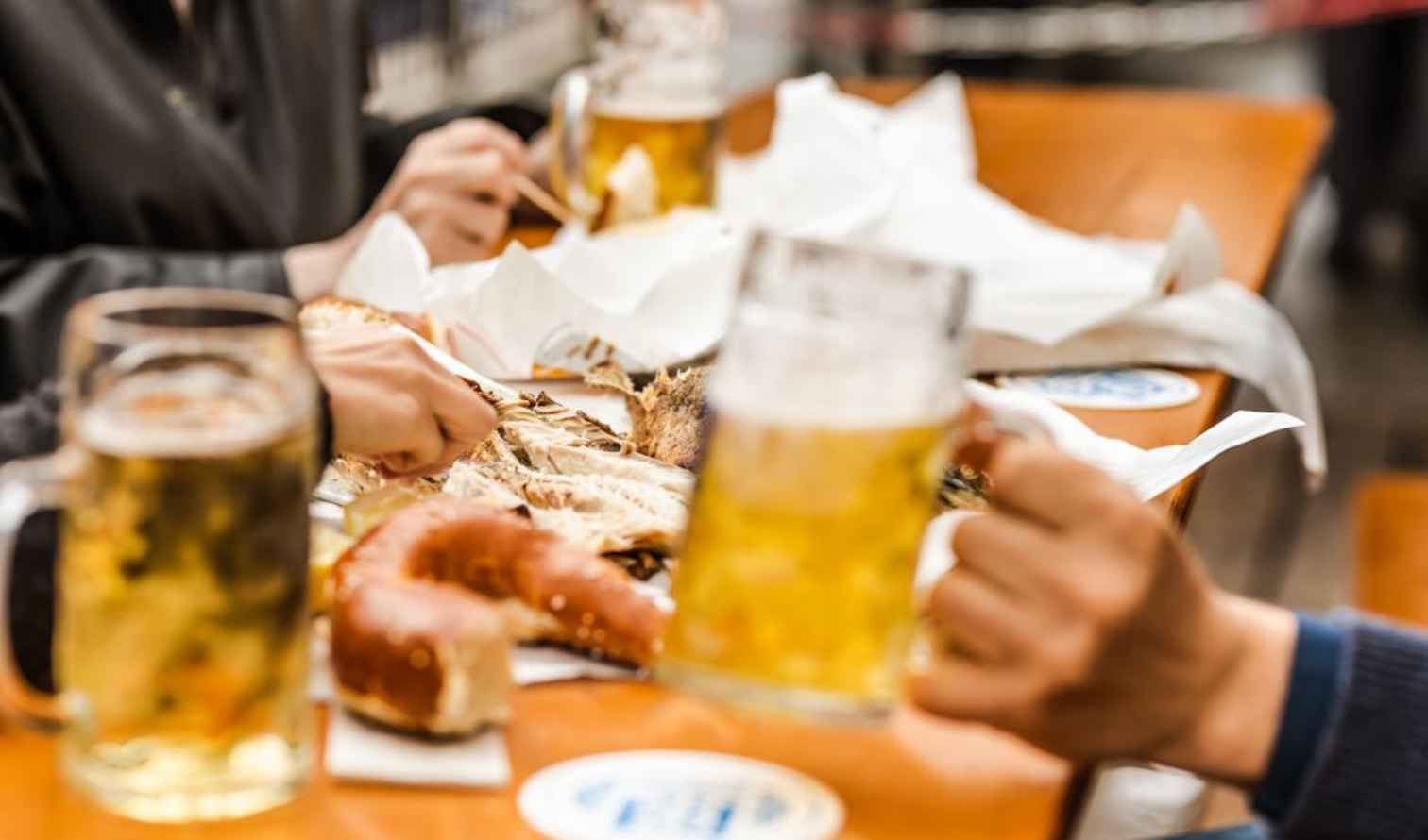 People enjoying beer and food at a wooden table in Munich
