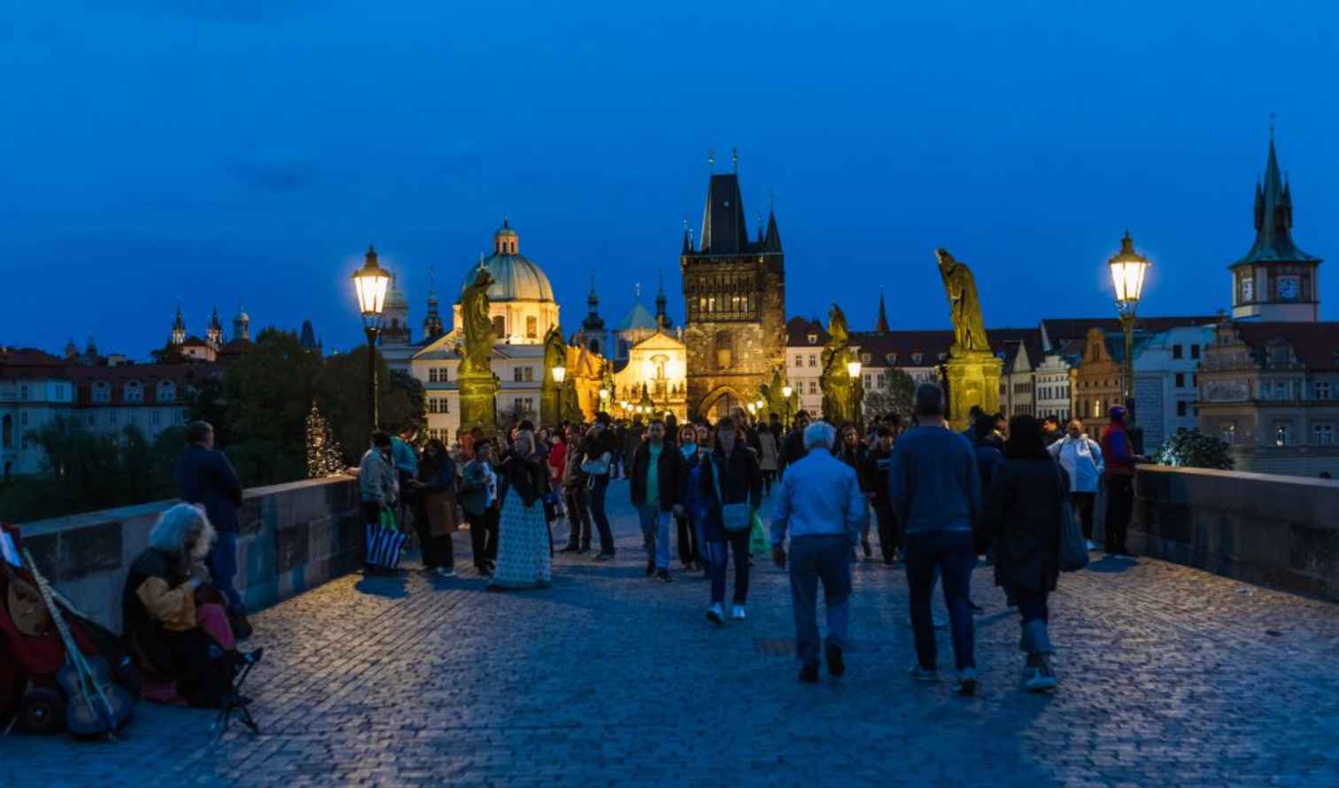 People walking on Charles Bridge in Prague during the evening.
