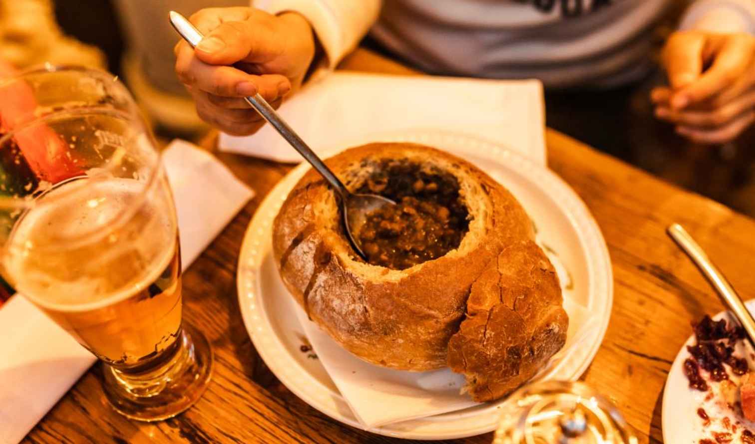 A person eating soup from a bread bowl at a restaurant in Prague