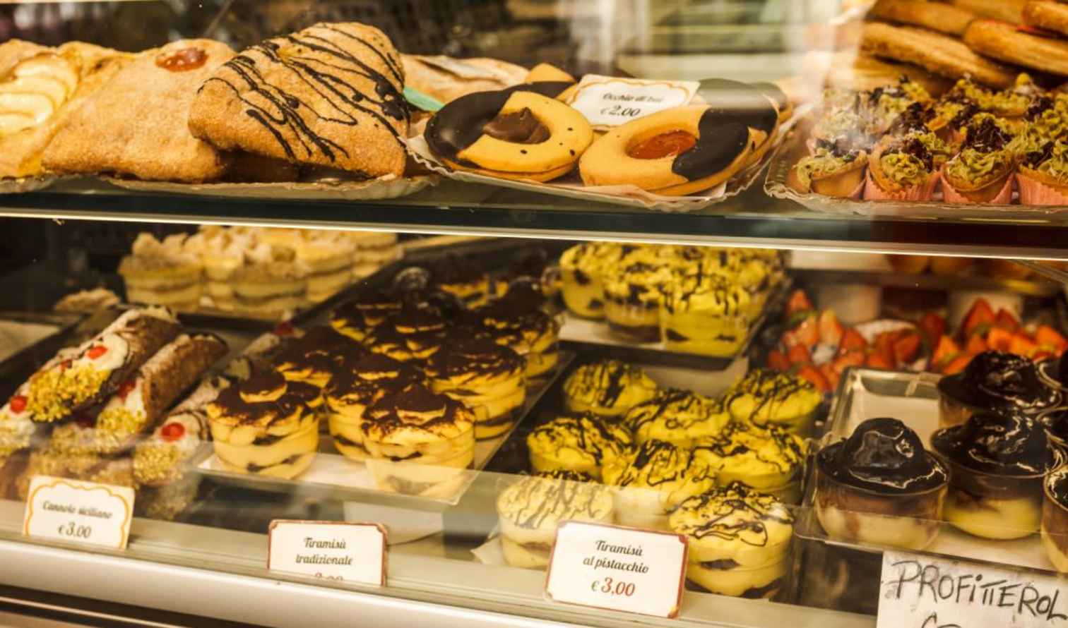 Assorted pastries and tiramisu displayed in a glass bakery case in Rome
