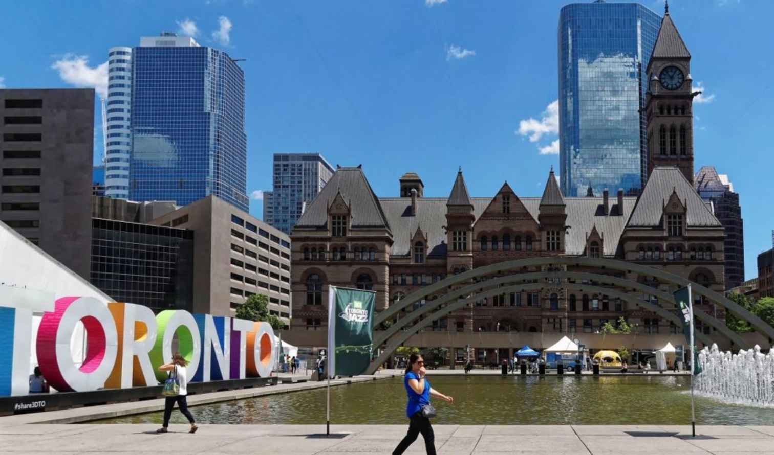 Old City Hall clock tower behind the Toronto sign in the foreground.