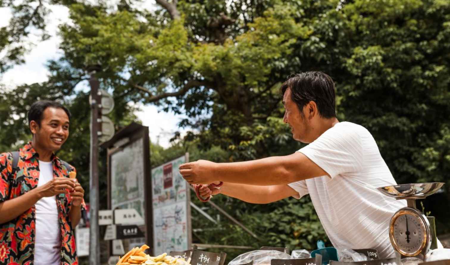 Two men exchanging goods at an outdoor market stand in Kyoto