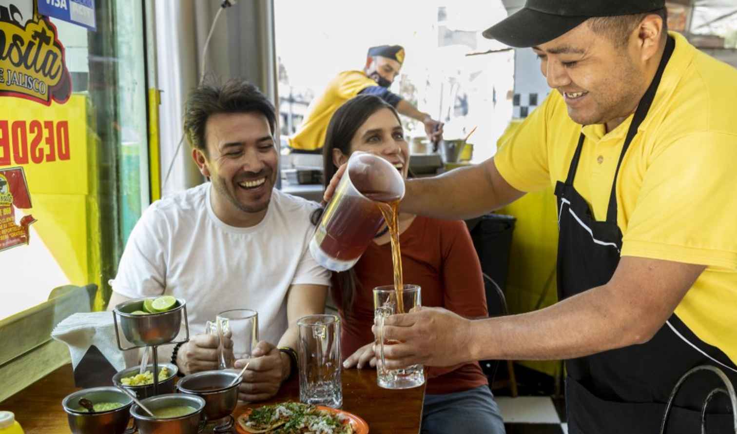 Server pouring drink for customers at La Rosita Jalisco, Mexico street restaurant.