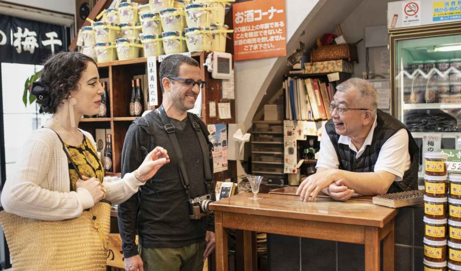 Two tourists converse with a shopkeeper in a Japanese sake shop in Tokyo