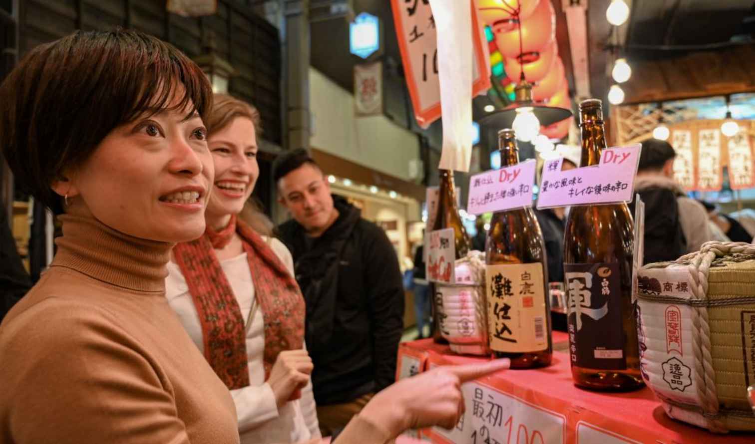 People examining sake bottles at Nishiki Market in Kyoto, Japan.