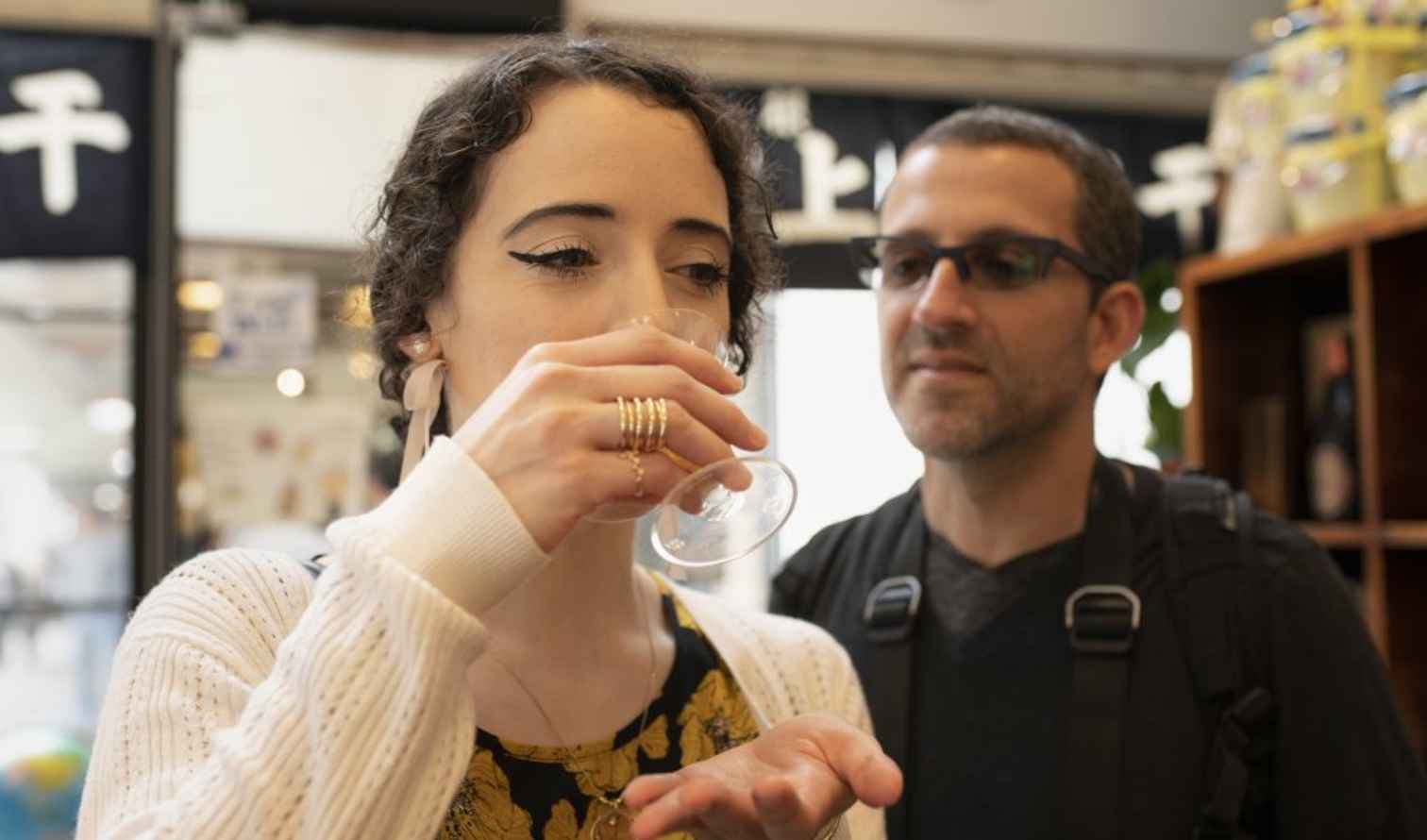 Two people inside a shop, one drinking from a glass in Tokyo