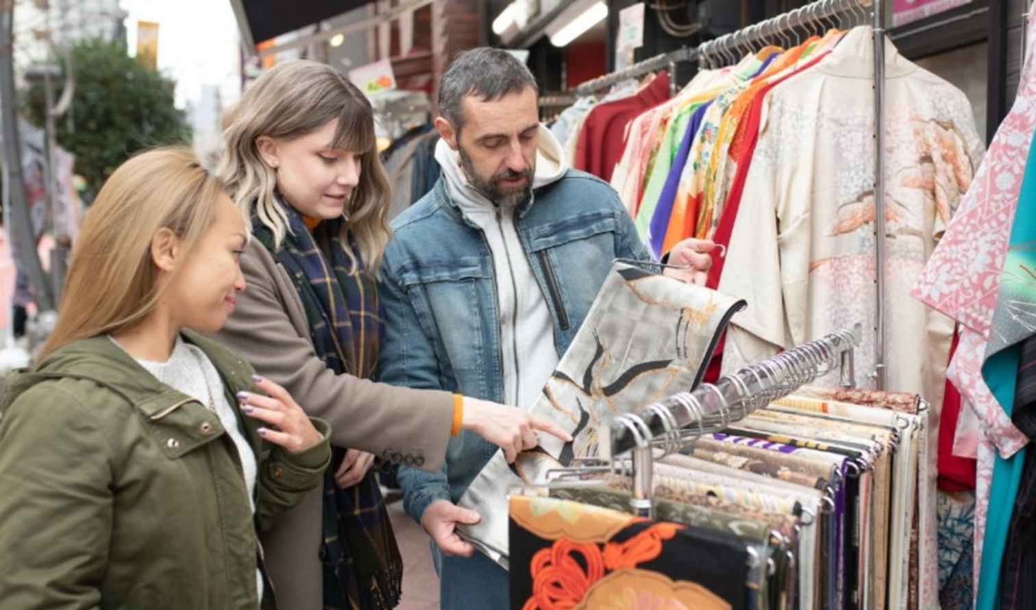 Outdoor market with kimono display and shoppers examining fabrics in Tokyo