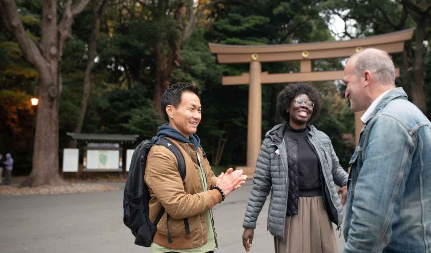 Three people standing in front of a torii gate at a park in Tokyo