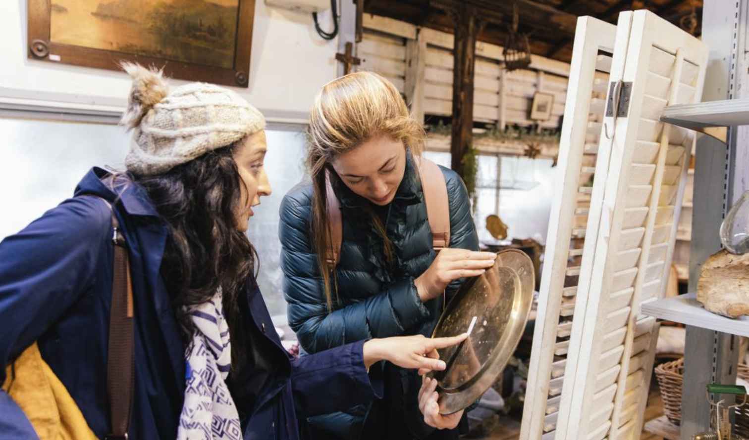 Two women examining a metal plate indoors in Tokyo