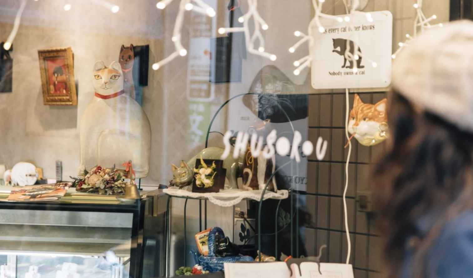A woman looks into a cat-themed store display in Tokyo