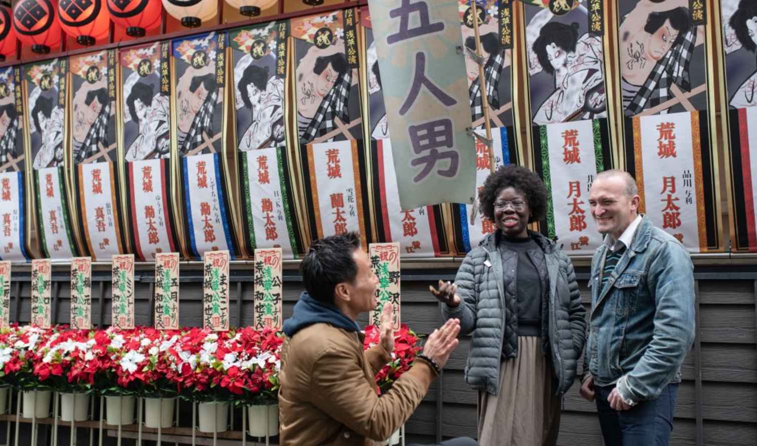 Group of people outside a kabuki theater with posters in Tokyo, Japan.