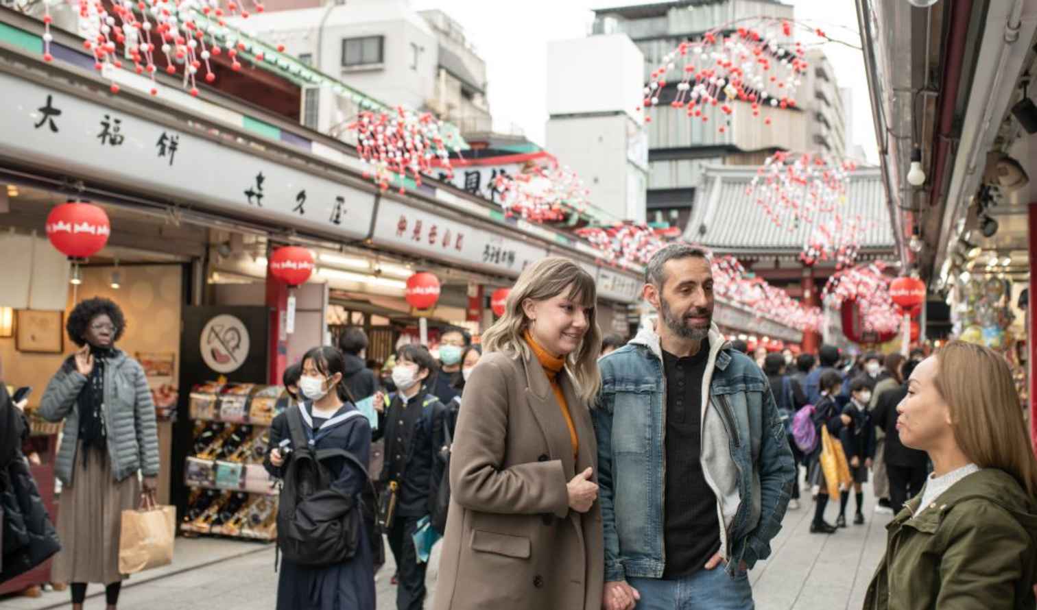 People walking in Nakamise Shopping Street, Tokyo, near traditional shops.