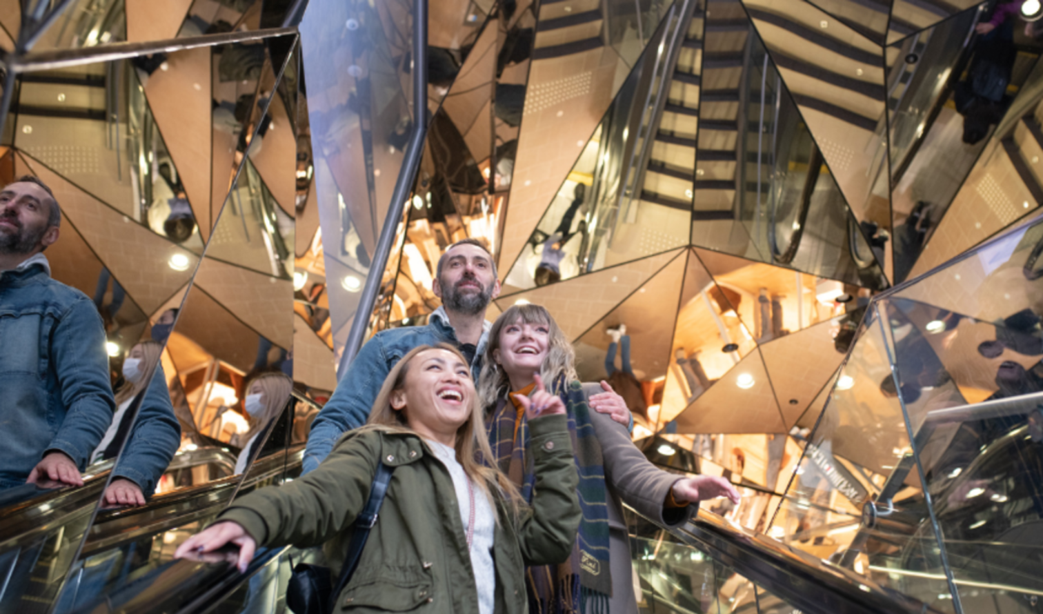 People on an escalator with mirrored walls at Tokyu Plaza Omotesando.