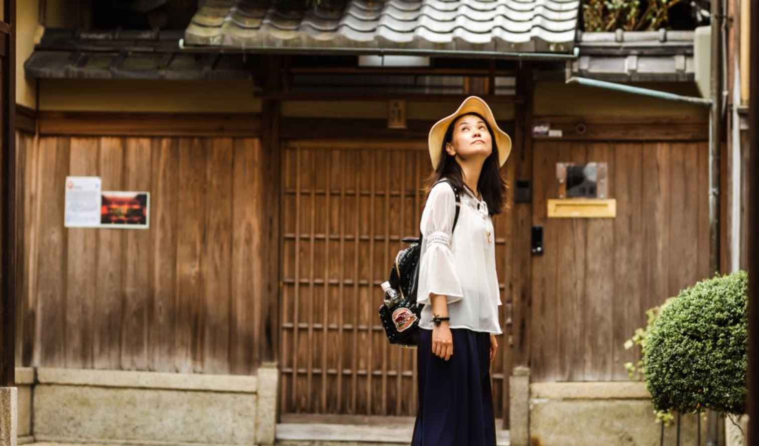 Woman standing in front of a traditional Japanese wooden building in Kyoto