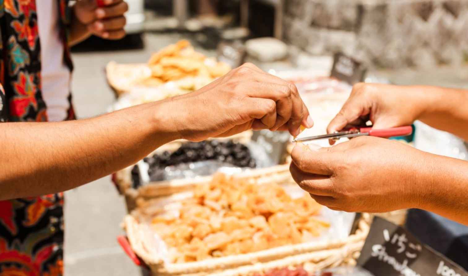 Hands exchanging a food sample at a street market in Kyoto