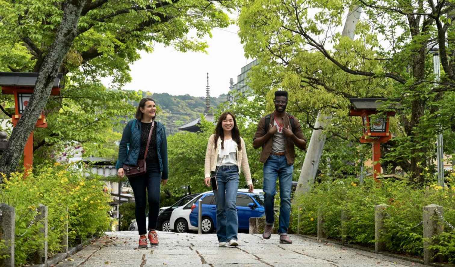 Three people walking on a path near Yasaka Pagoda in Kyoto, Japan.