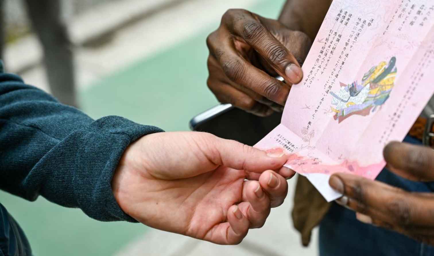 Two people examining a fortune slip at a Japanese temple in Kyoto