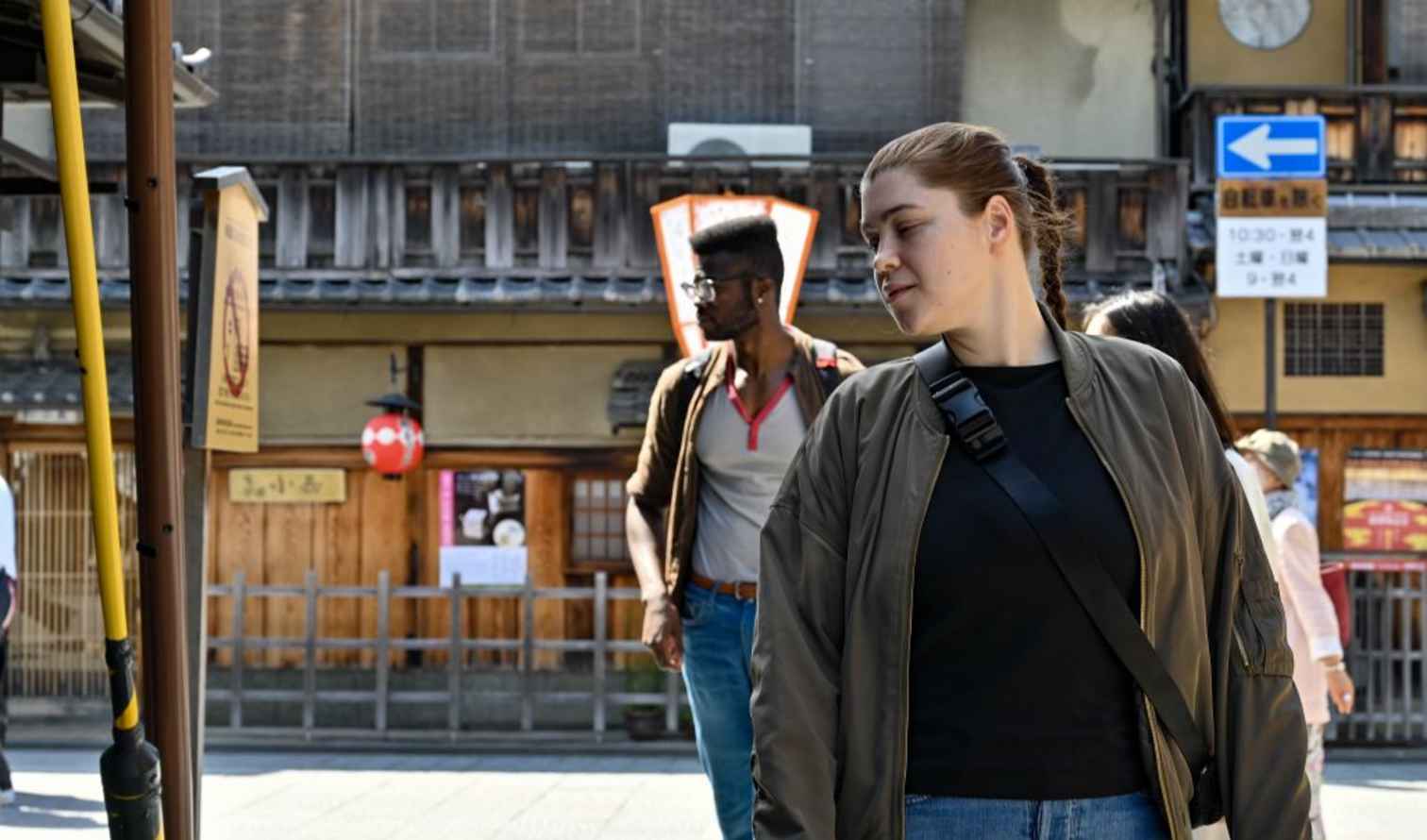 People walking on a street in Gion, Kyoto, Japan with traditional wooden buildings.