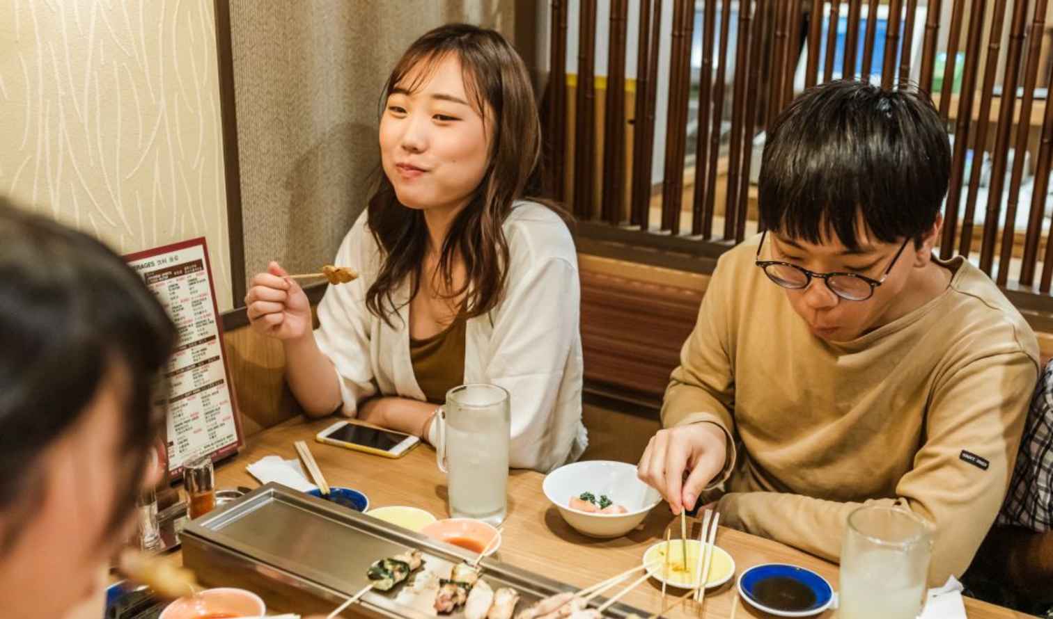Two people eating at a wooden table in a Japanese restaurant in Kyoto