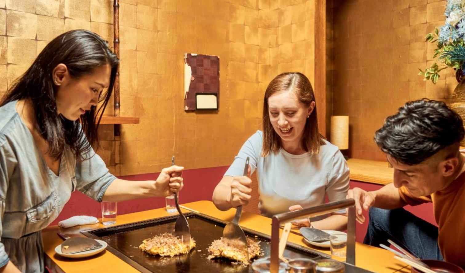Three people cooking on a teppanyaki griddle in a Japanese restaurant in Osaka