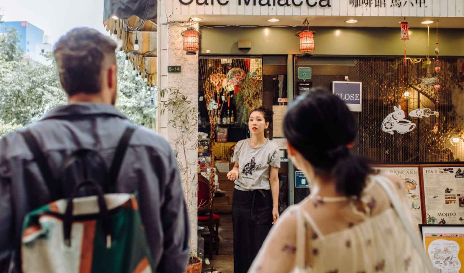 A man and woman stand outside Cafe Malacca, looking at the entrance in Osaka