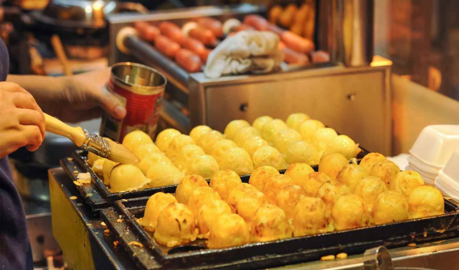 Takoyaki grilling at a food stall in an urban setting in Hong Kong.