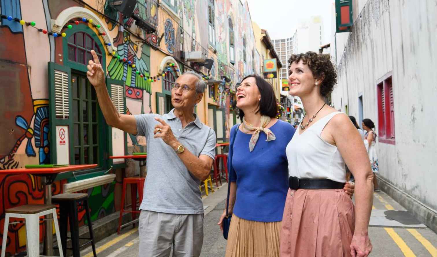 Group of three people in an alley with colorful murals in Singapore