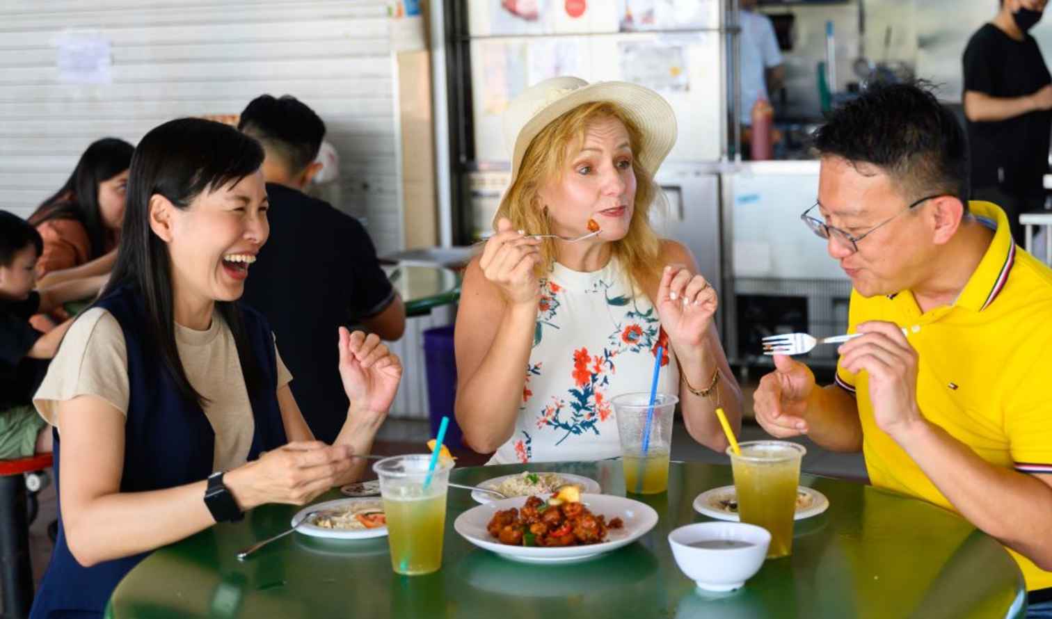 Three people sharing a meal at a hawker center in Singapore.