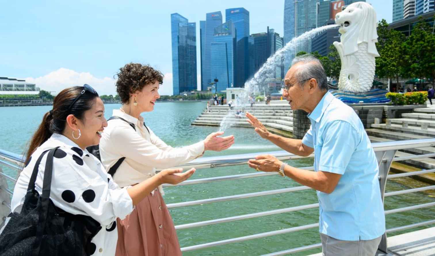 Three people interacting near the Merlion Park in Singapore.