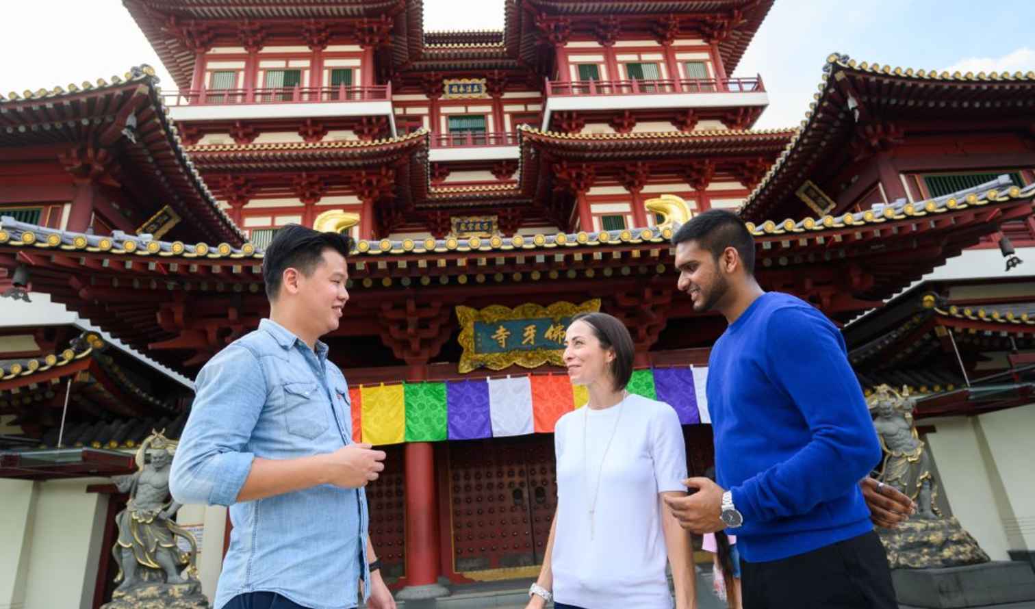 Three people stand in front of the Buddha Tooth Relic Temple, Singapore.