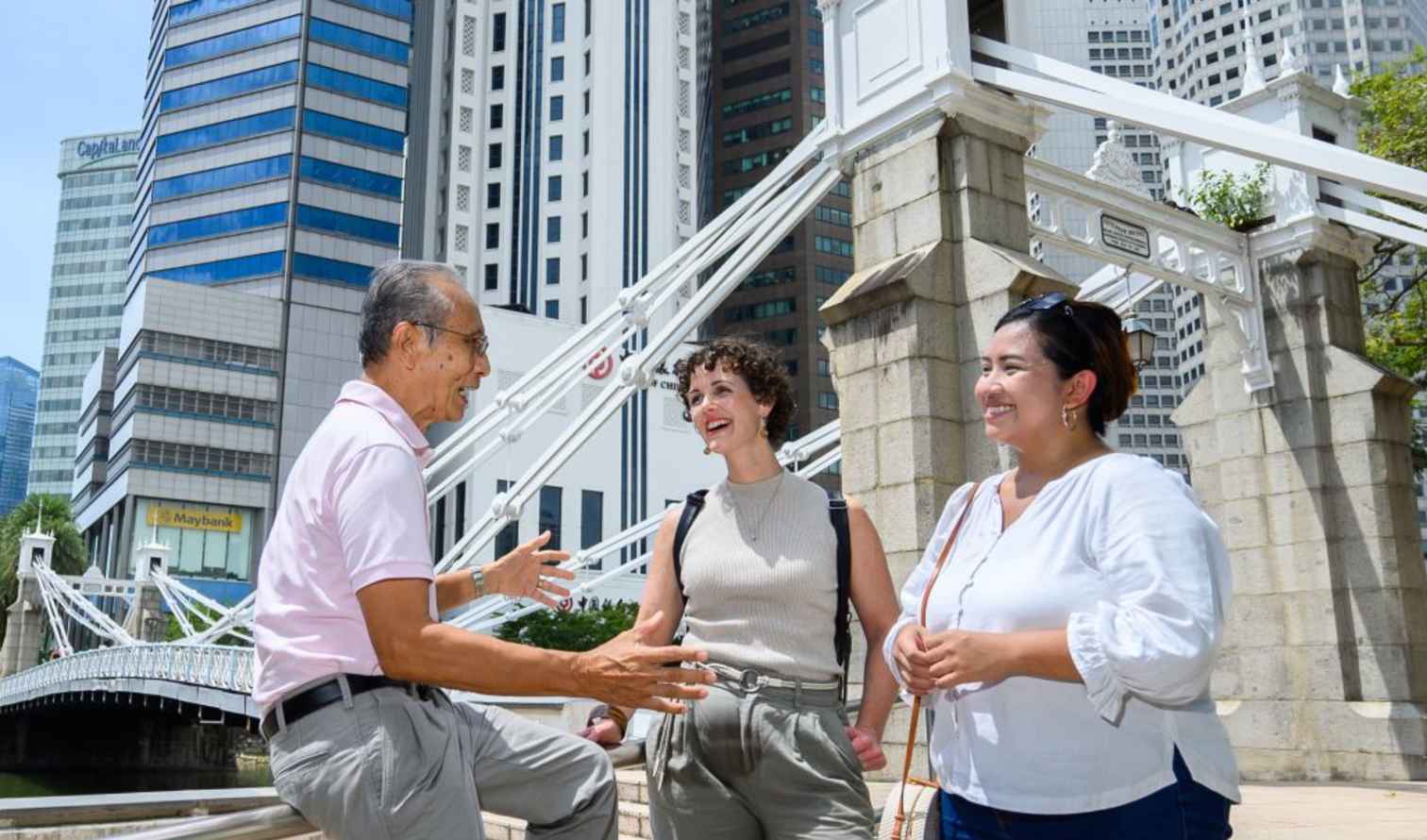 Cavenagh Bridge visible, with three individuals conversing in Singapore cityscape.