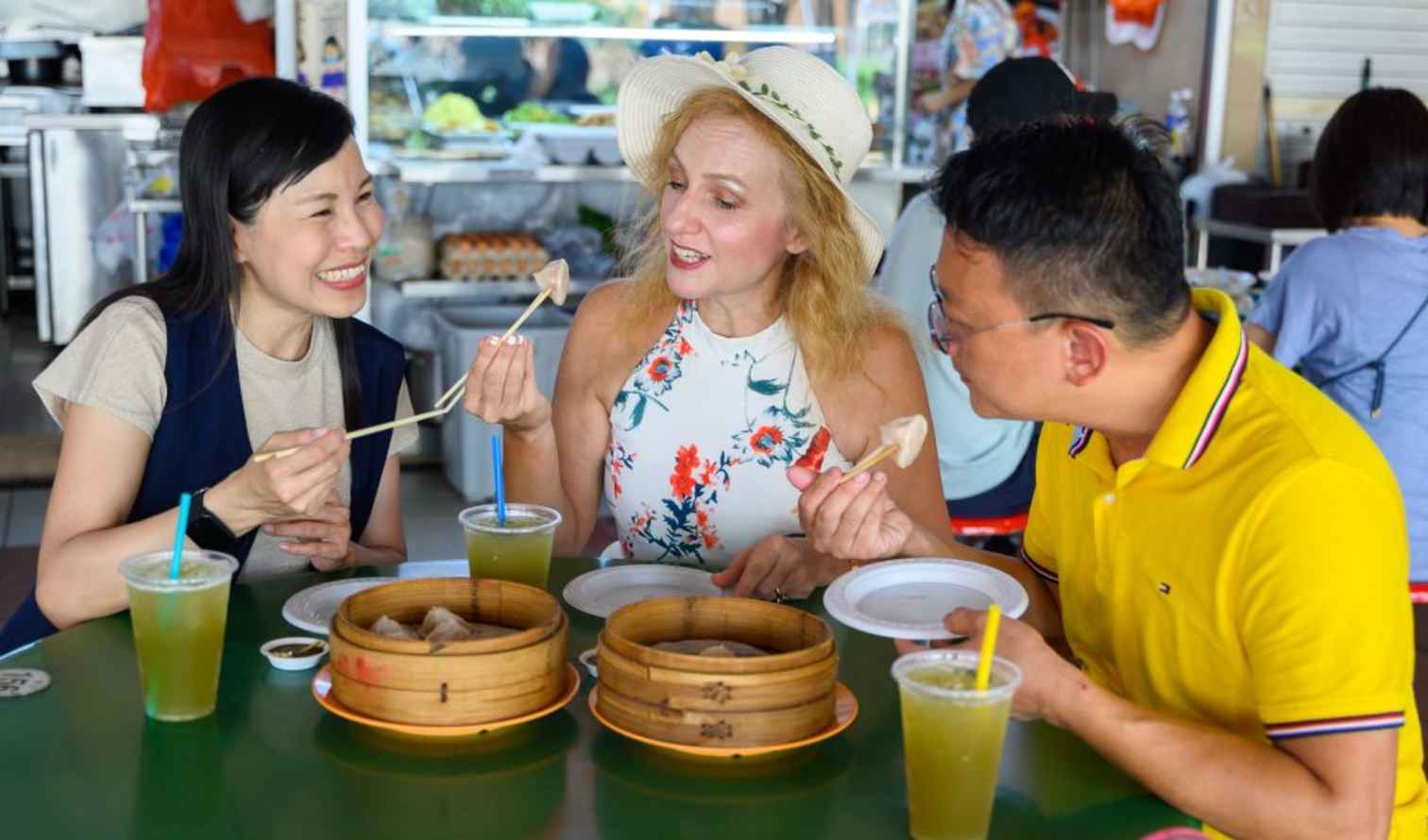 Three people eating dim sum at a hawker center in Singapore.