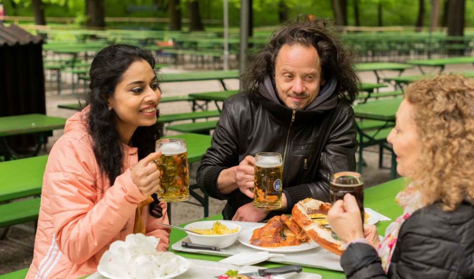 Friends sharing a meal outside with beer glasses at a park in Munich