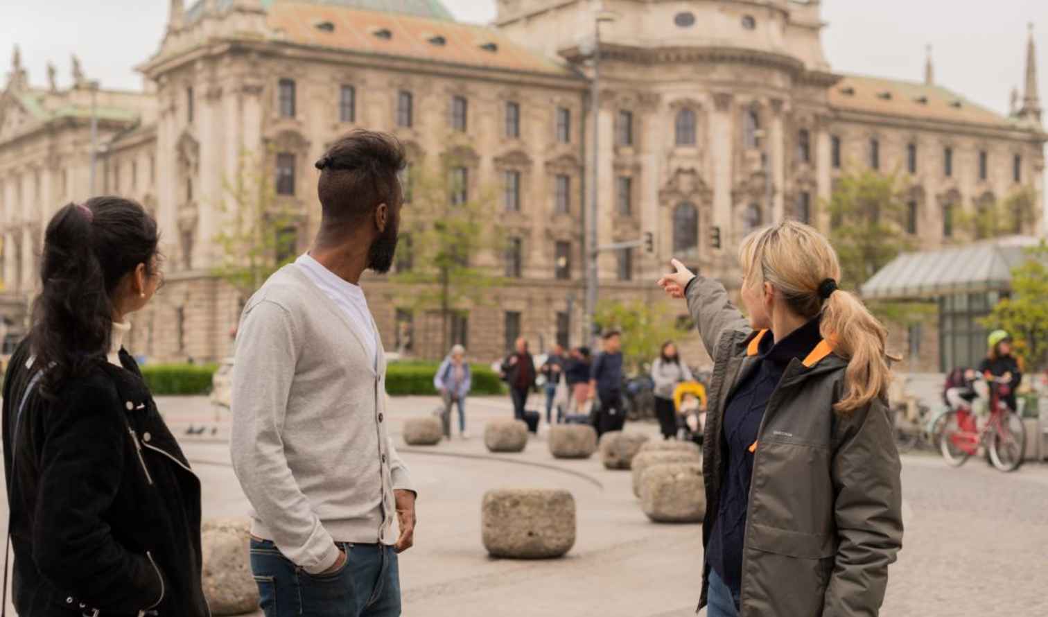 People standing in Karlsplatz, Munich, with a historic building in the background.