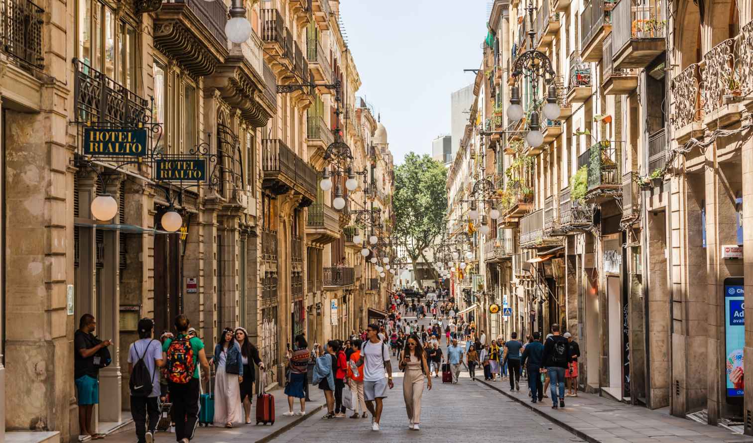 People walking along a street with Hotel Rialto signs in Barcelona.
