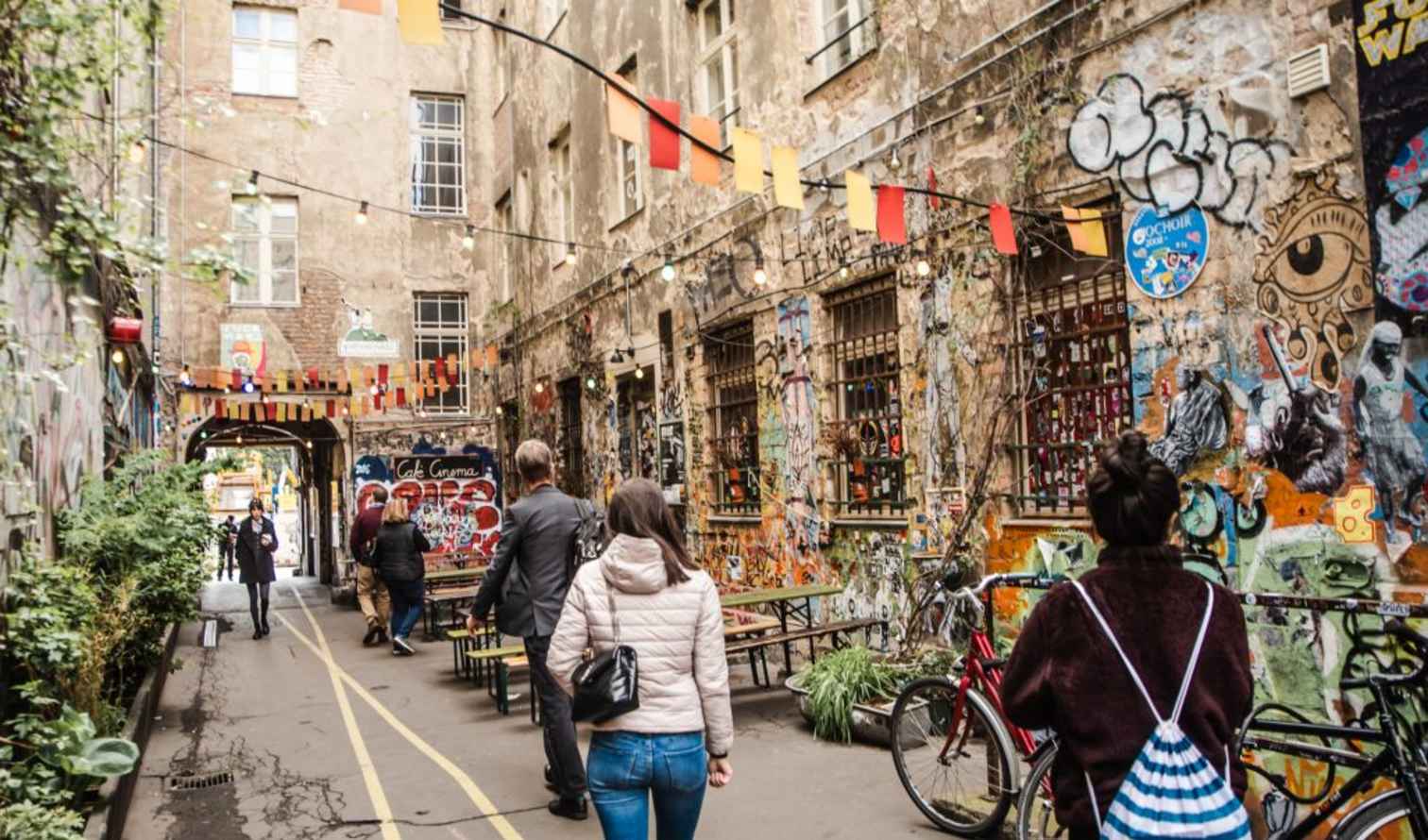 People walking through a graffiti-covered alley in Hackescher Markt, Berlin.