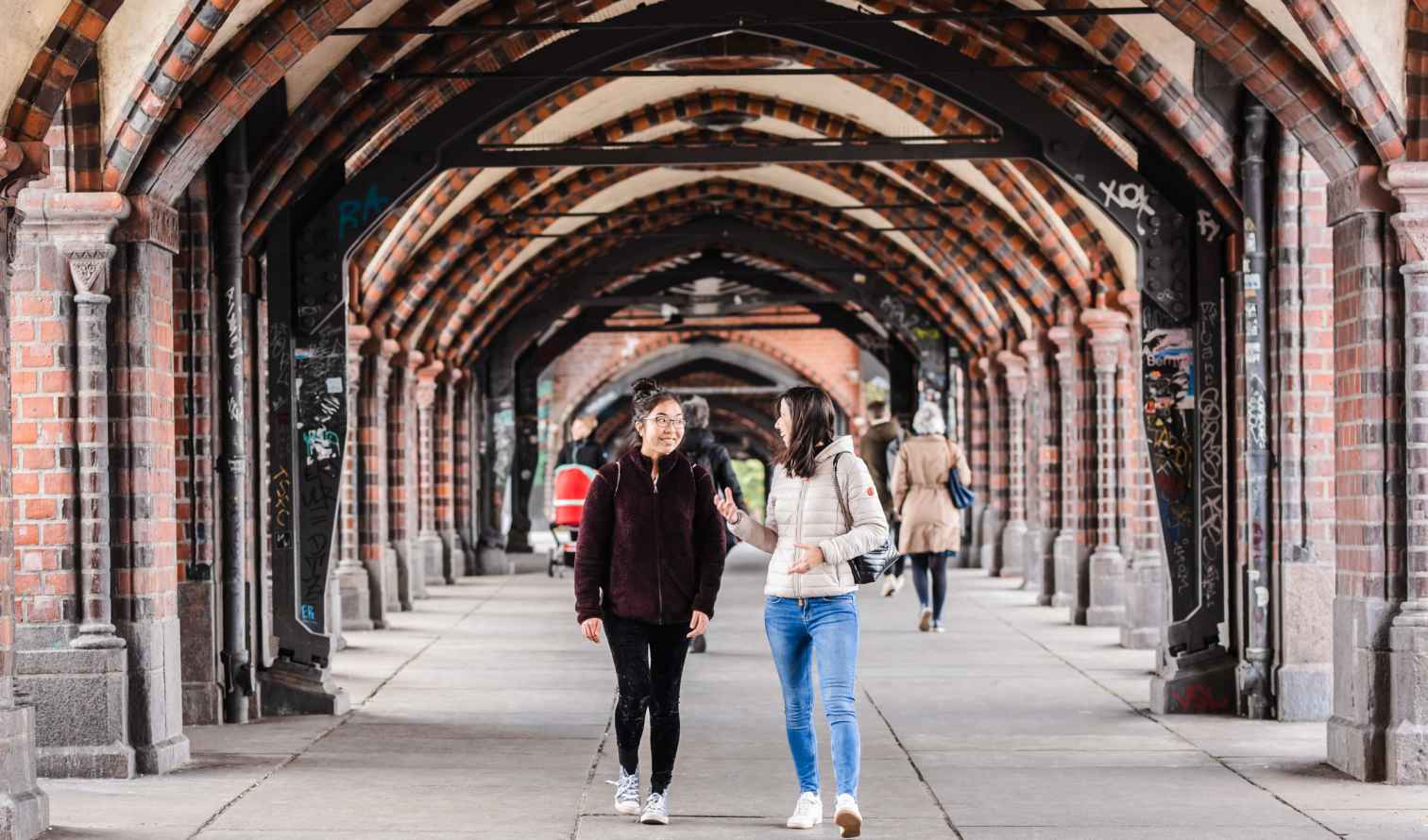 People walking under the arches of Oberbaum Bridge in Berlin.