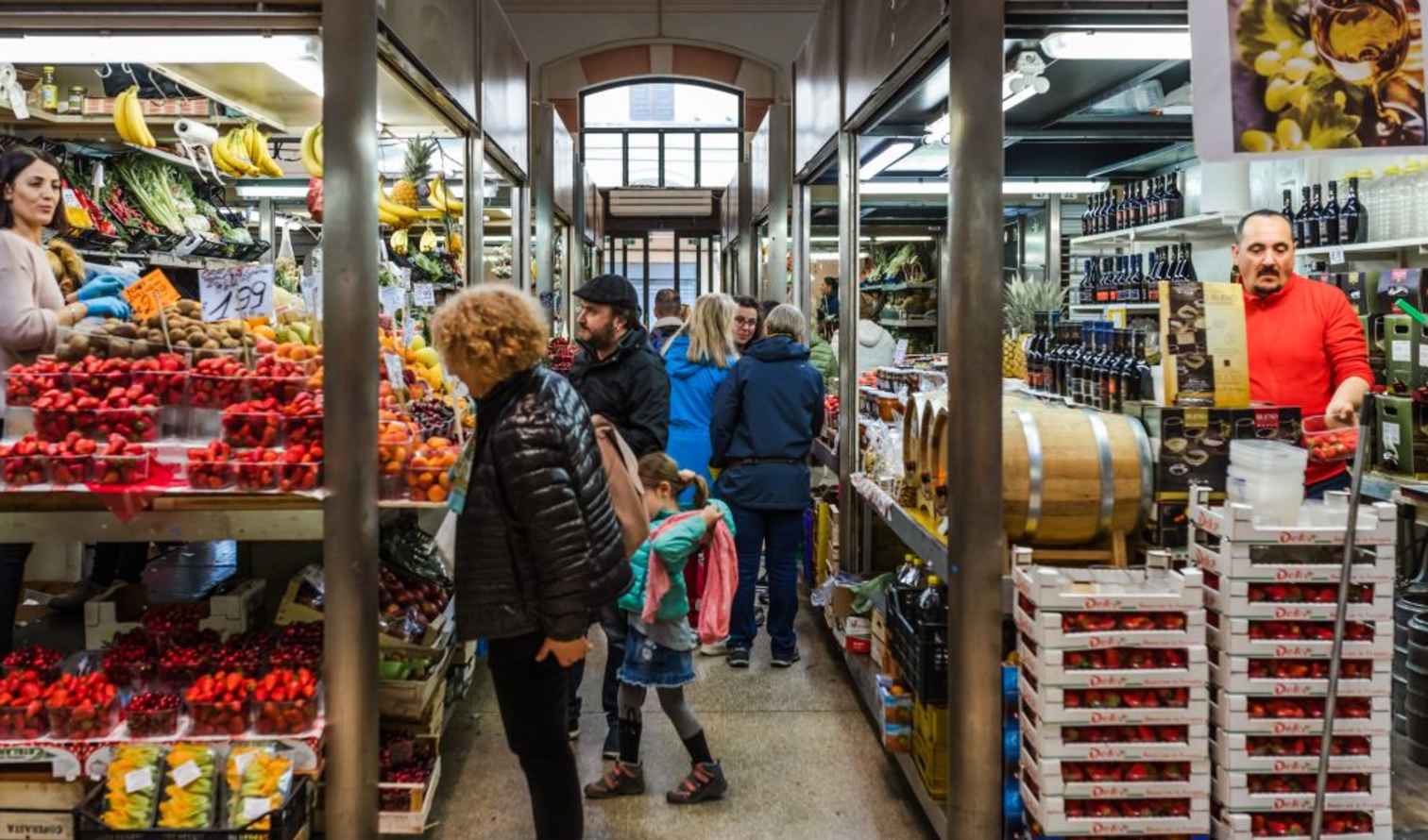 Indoor market scene with people shopping at Mercato di Mezzo, Bologna.